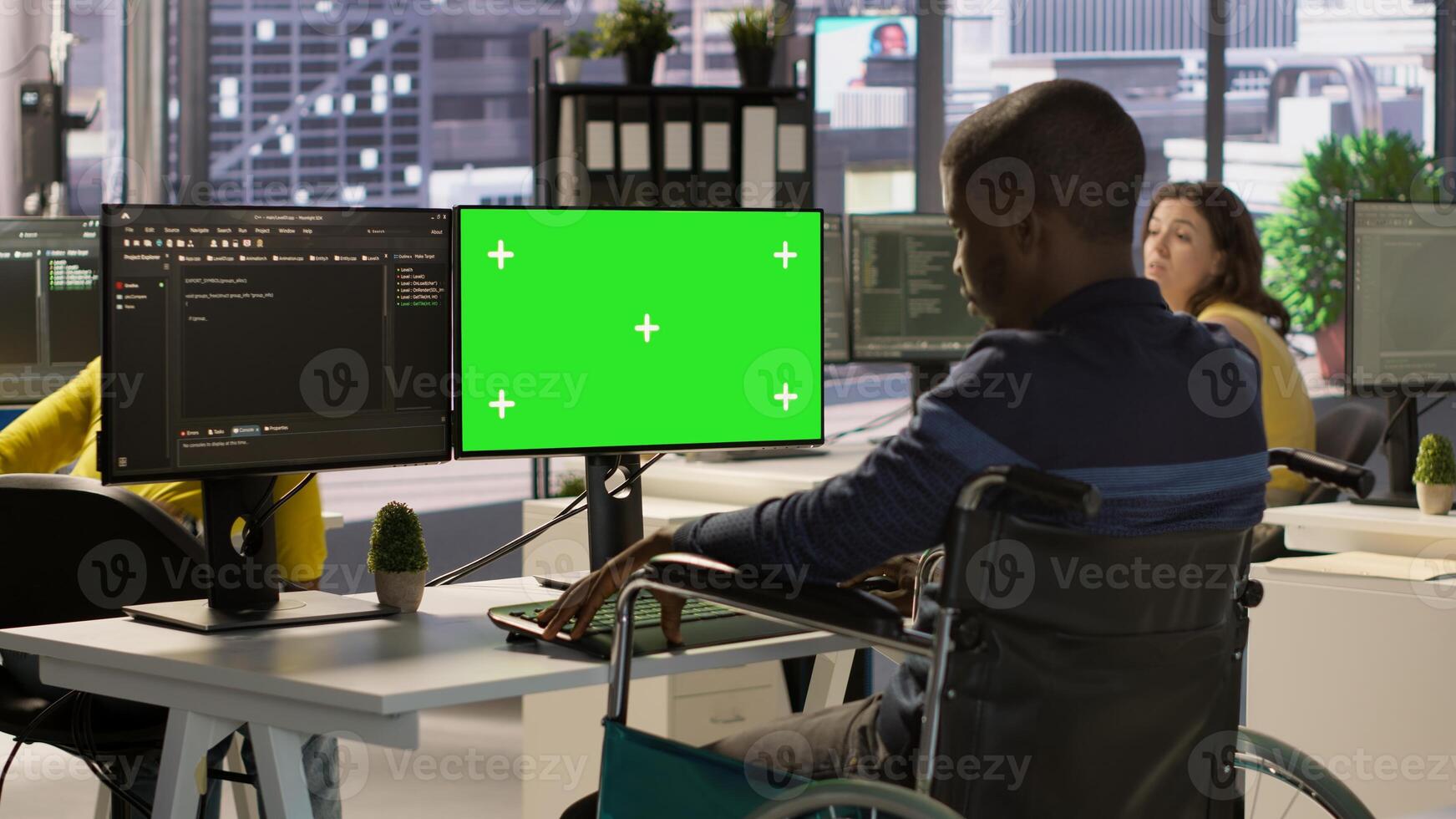 Person with disability testing and deploying programs and systems on green screen PC. Software technician in wheelchair checking code on mockup PC, sitting at desk in office, camera A photo