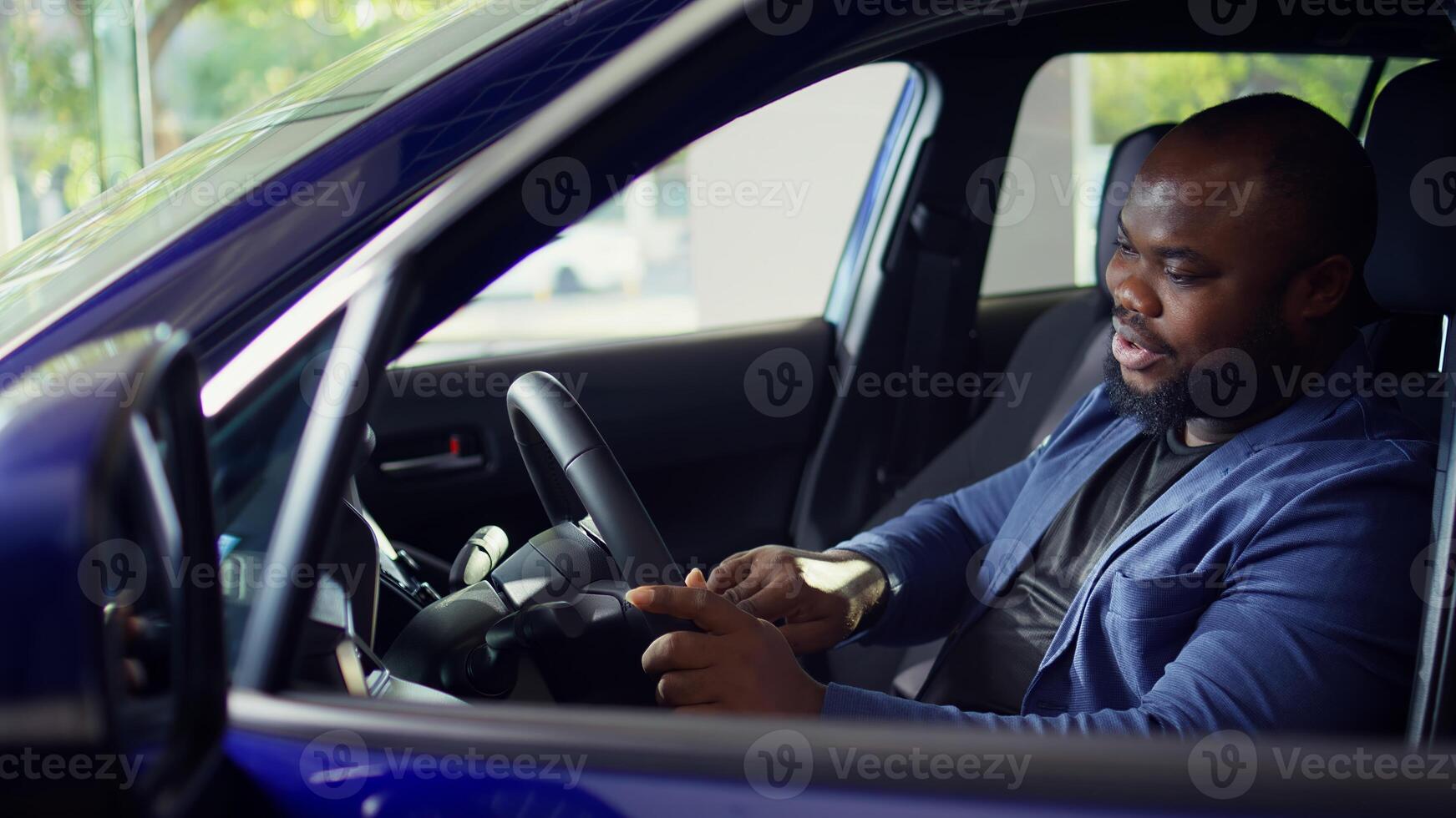 Man doing test drive, examining car before making purchase, exploring compartments and pushing buttons to make sure everything is working, checking how comfortable driving position is, camera B photo