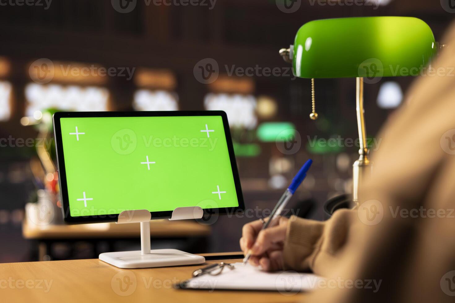 University scholar writes new project ideas next to green screen on tablet, gathering citations from reliable books and other sources at the library. Girl consulting the educational materials. photo