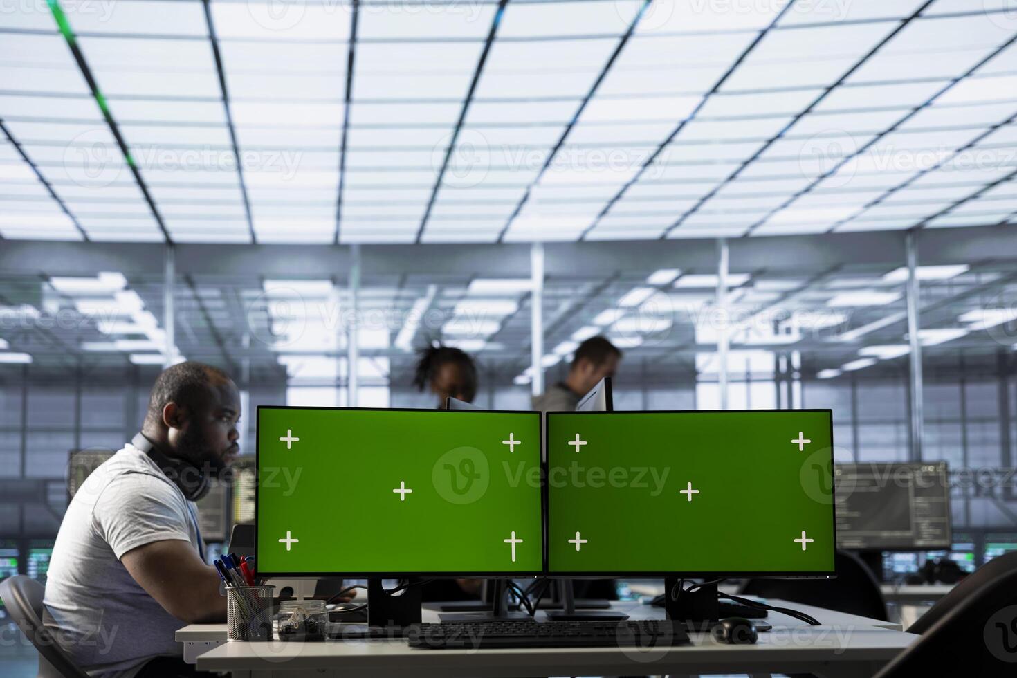 Green screen PC multi monitor setup in server hub workspace used by team of engineers to repair devices storing datasets. Chroma key computer used by workers for servicing rigs doing operations photo