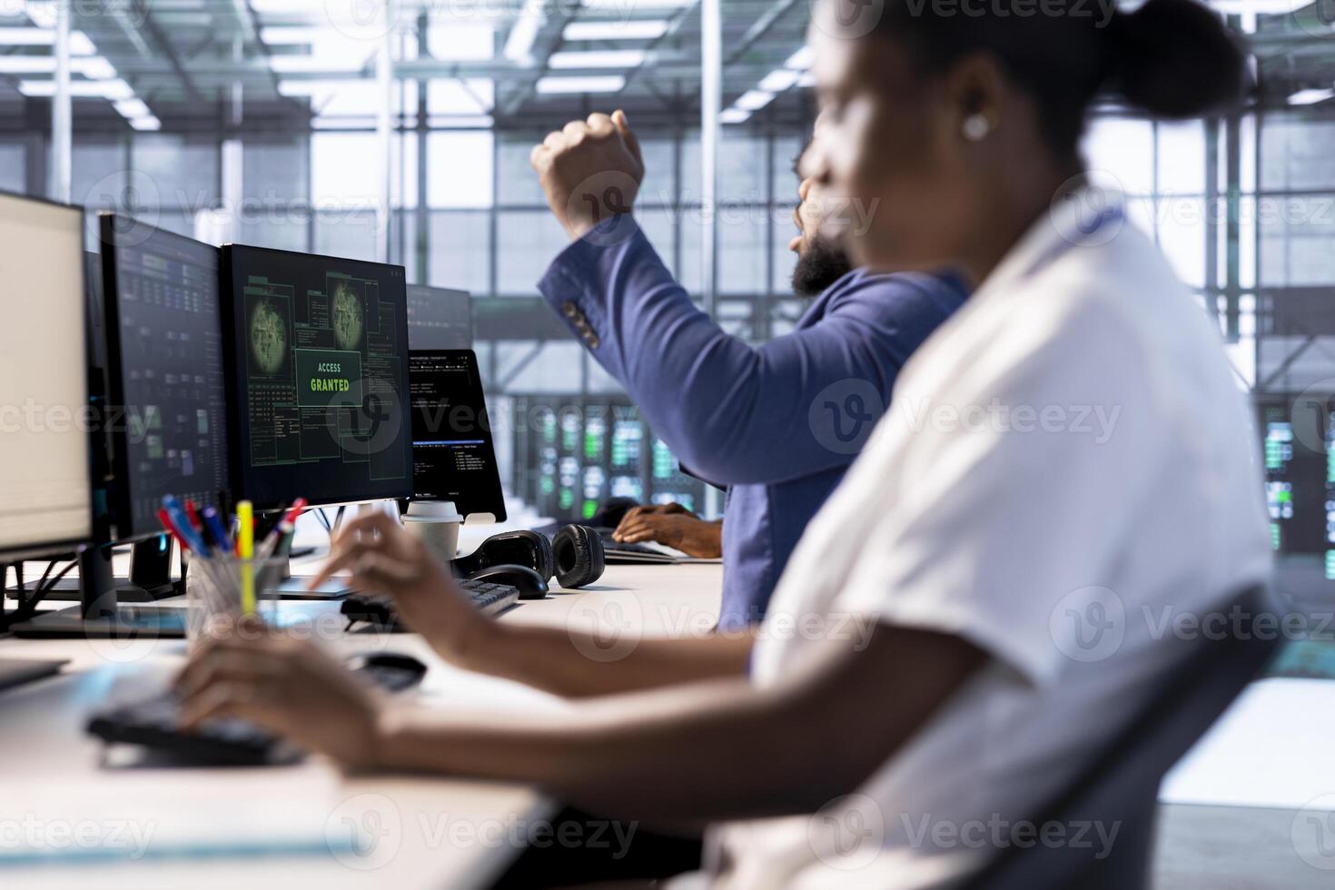 Admin in server farm celebrating after getting access granted, managing to access files after they were locked by hacker using ransomware, receiving aid from IT experts, doing hand gesture photo