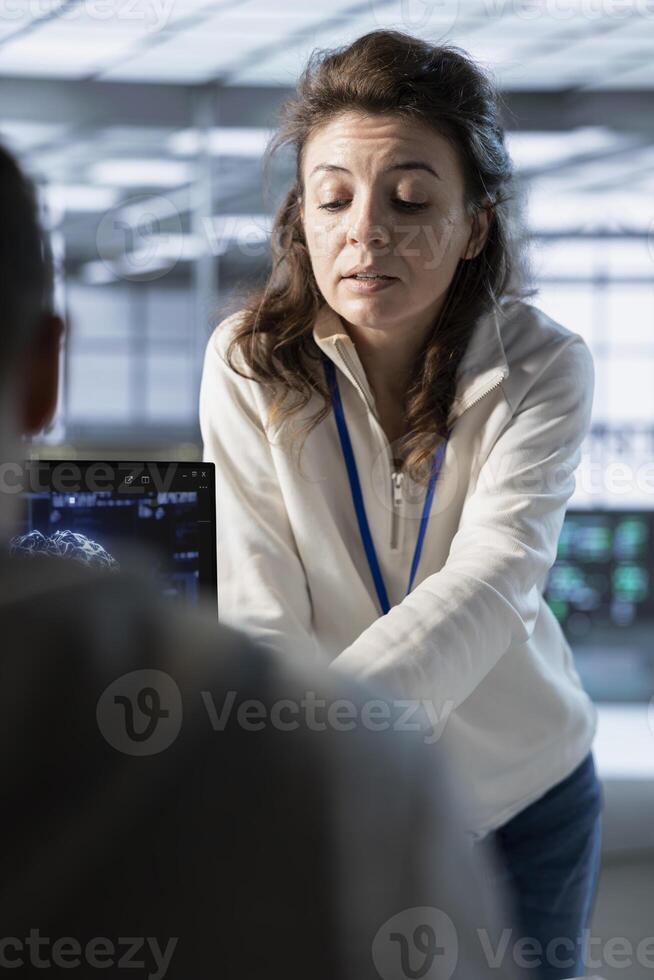 Manager overseeing workers in data center, coordinating deployment of server architecture, improving data processing. Supervisor checking progress done by employees in server farm testing equipment photo