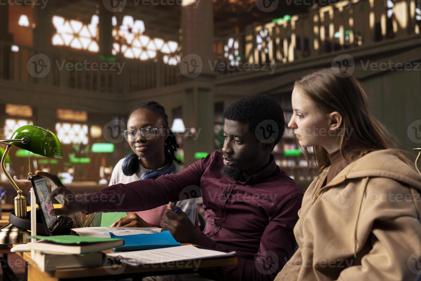 Multicultural students group discussing a financial project for a university course, using laptop and textbooks with class notes in the library. Work on entrepreneurship and management skills. photo