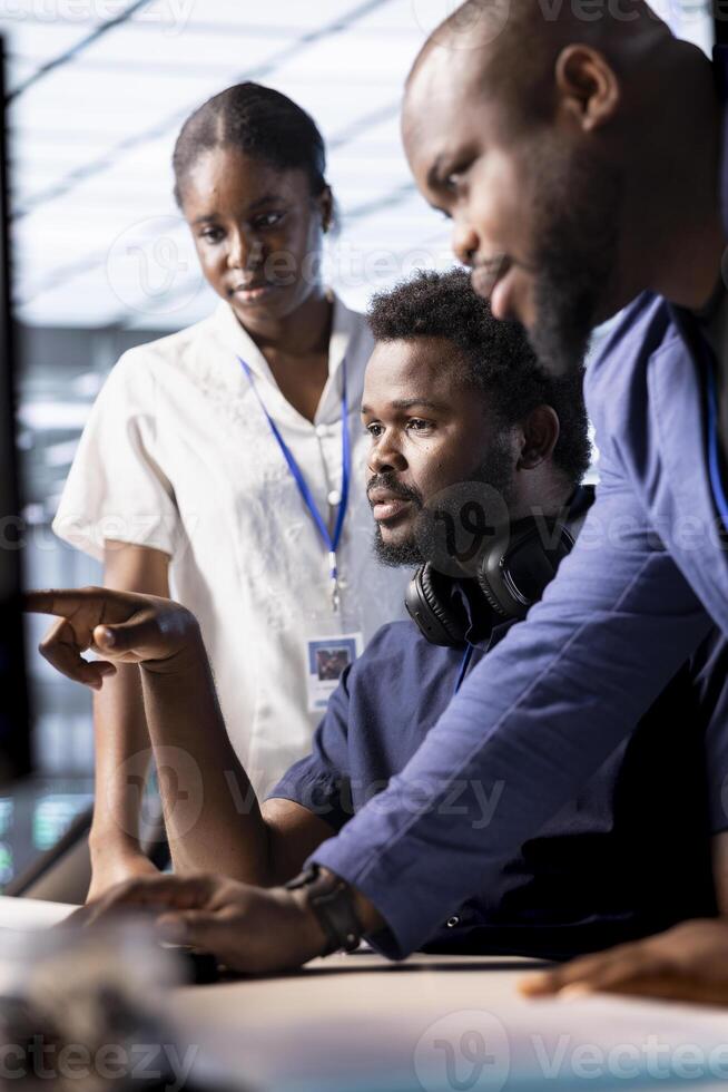 Team of cybersecurity experts monitoring security incidents affecting server hub network, working together. Engineering coworkers doing brainstorming in data center protecting company from threats photo