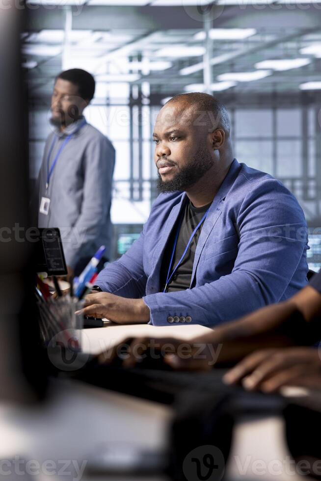 Cybersecurity technician monitoring security incidents affecting server hub workspace. System administrator in data center protecting company critical infrastructure from cyber threats photo