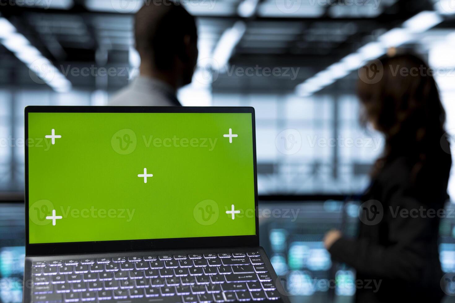 Focus on green screen laptop used by computer scientists in data center inspecting servers, updating network topologies. Close up of mockup notebook next to team of IT professionals IT photo
