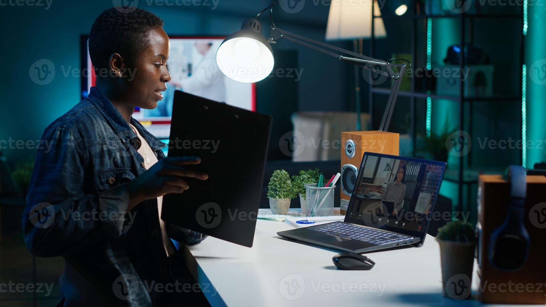 Manager talking with collaborator working from home, holding teleconference meeting to present project. Team leader talking with employee showing charts on clipboard during online videocall, camera A photo