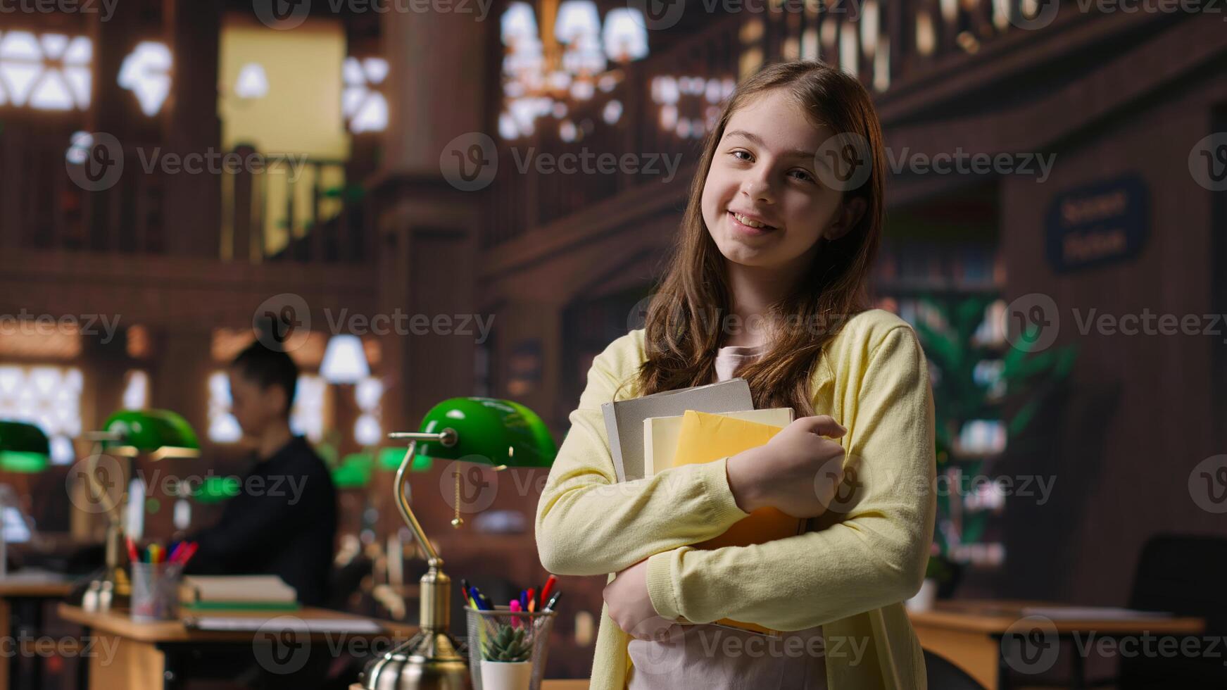 Portrait of cute young schoolgirl entering the library to study in peace, carrying textbooks and learning materials. Preteen scholar preparing for her school lessons, homework session. Camera B. photo