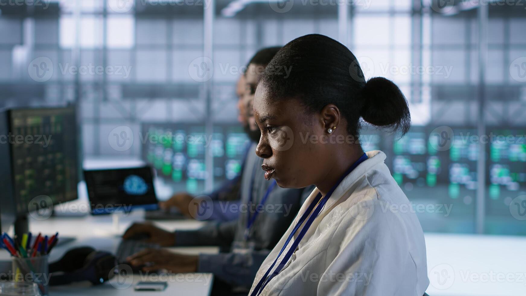 African american data center technicians implement AI predictive maintenance systems. Woman in server hub using artificial intelligence to identify hardware failures, camera A photo