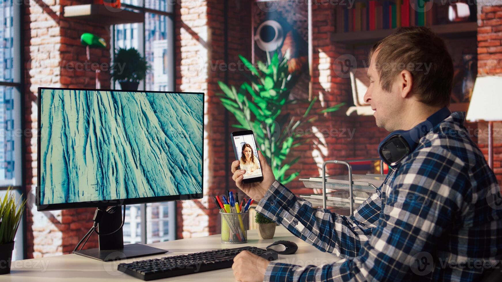 Man in home office looking at social media feed with live broadcasts from online content creators. Employee at work using social network application with livestreams done by influencers, camera A photo