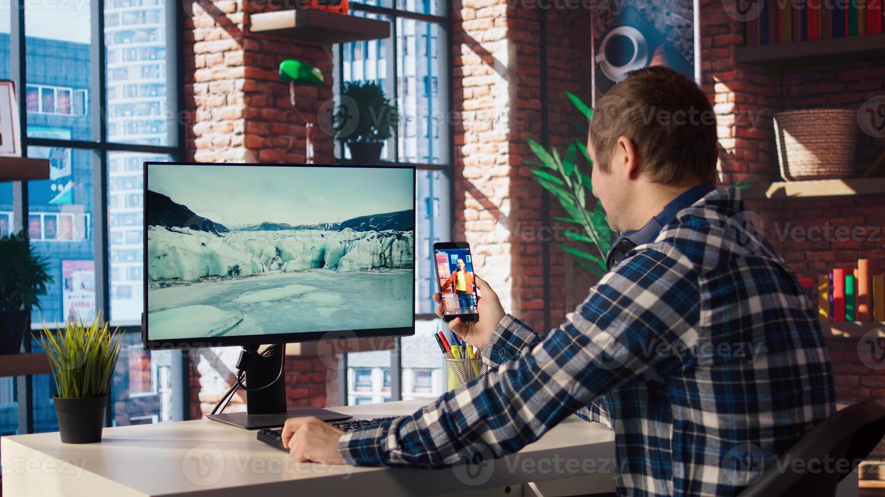 Man at home having fun looking at social media reels done by online content creators. Employee taking break from work to use mobile social network app, screensaver activating on PC, camera A photo