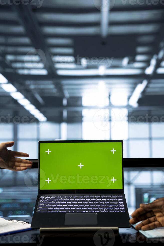 Computer scientists in data center using chroma key green screen laptop, refining server virtualization strategies. Server hub workers using mockup notebook to configure cluster nodes photo