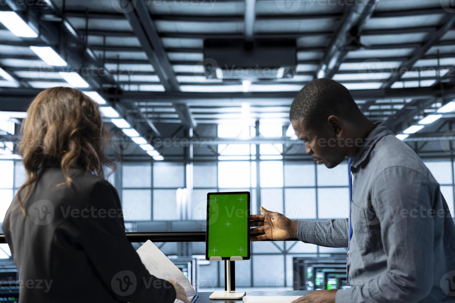Technicians in data center using green screen mockup tablet, reviewing hardware diagnostics, clearing error states, adjusting device configurations, applying firmware updates photo