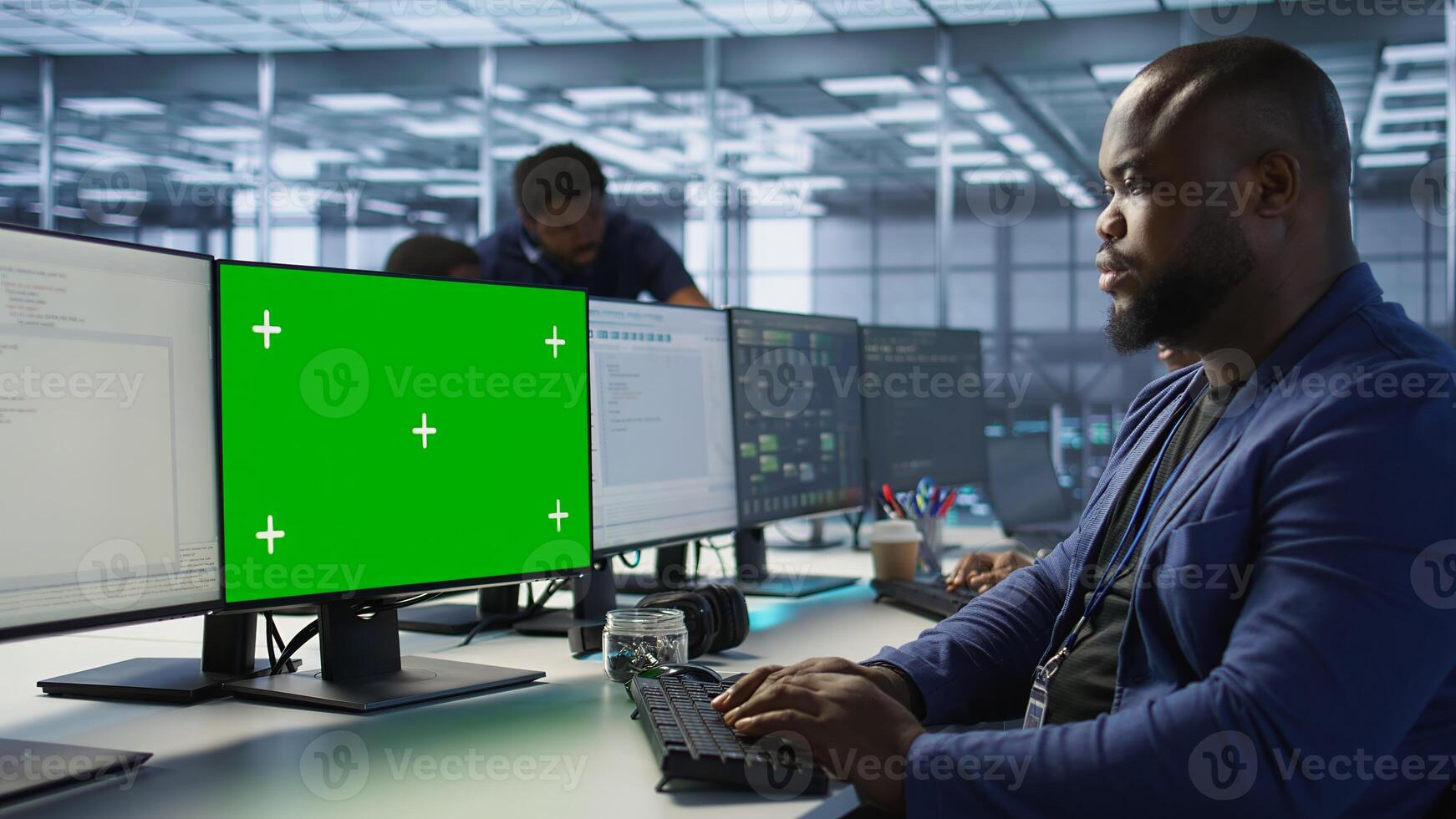 African american data center admin using mockup PC, maintaining company network infrastructure. Man working in server farm ensuring optimal system performance with green screen computer photo