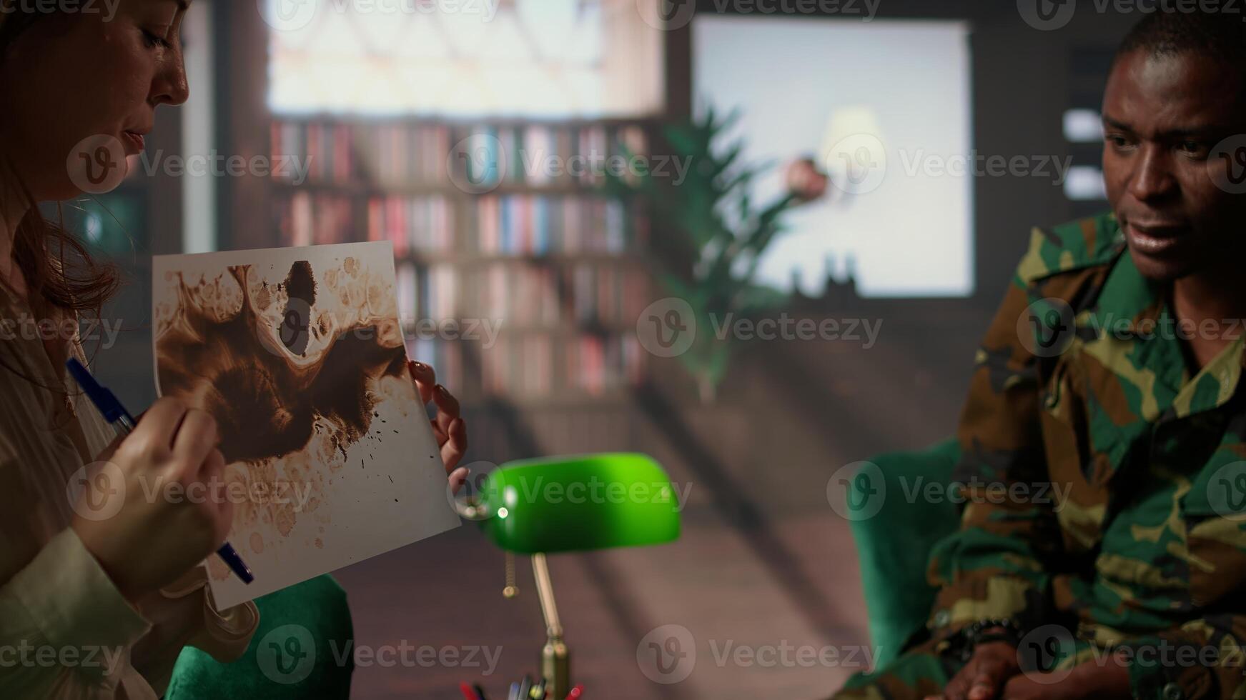 Military veteran studies Rorschach inkblot in therapy session with counselor, addressing PTSD and trauma recovery problems. Woman shows psychological support for mental health care. Camera A. photo