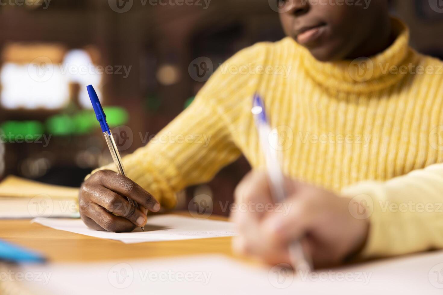 Diverse preteens writing class notes in their notebooks at a library desk, preparing for an academic assessment after classes. Literary ideas on paper, emphasizing child development. Close up. photo