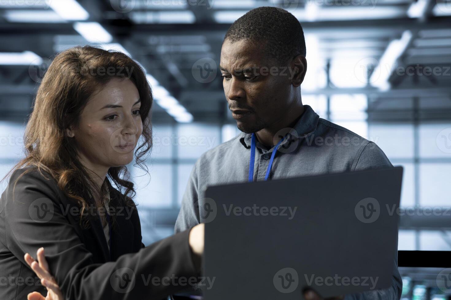 Employees in data center using laptop, integrating green technologies. Server room IT experts doing brainstorming, implementing sustainable energy solutions to maintain environmental standards photo