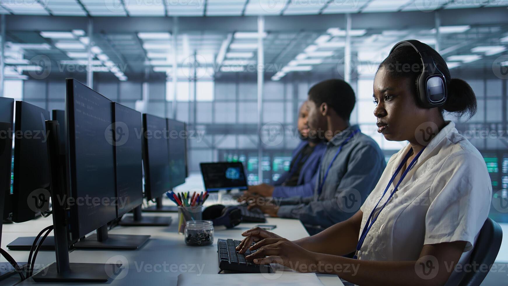 Portrait of smiling engineer hearing podcasts to make time pass faster while working in server farm to optimize it for data processing requirements. Happy woman listens songs in data center, camera A photo