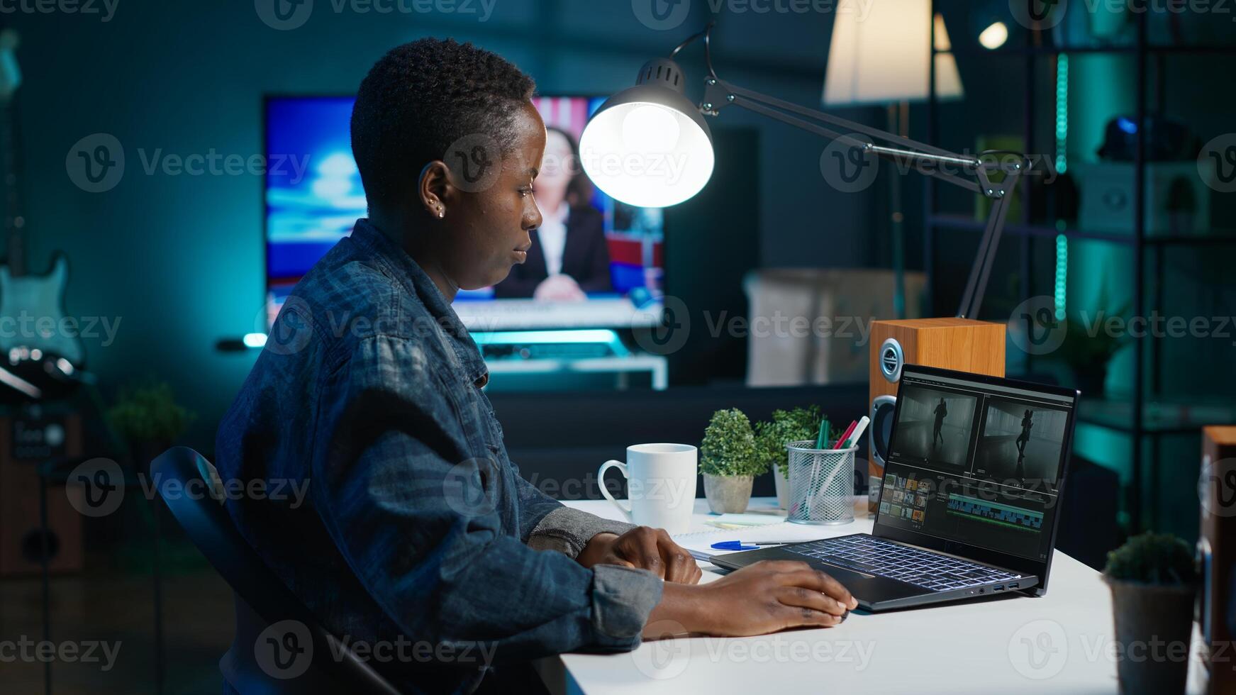 Remotely working videographer doing montage using specialized software applications. African american editor using editing tools on laptop to cut movie project footage in office, camera A photo