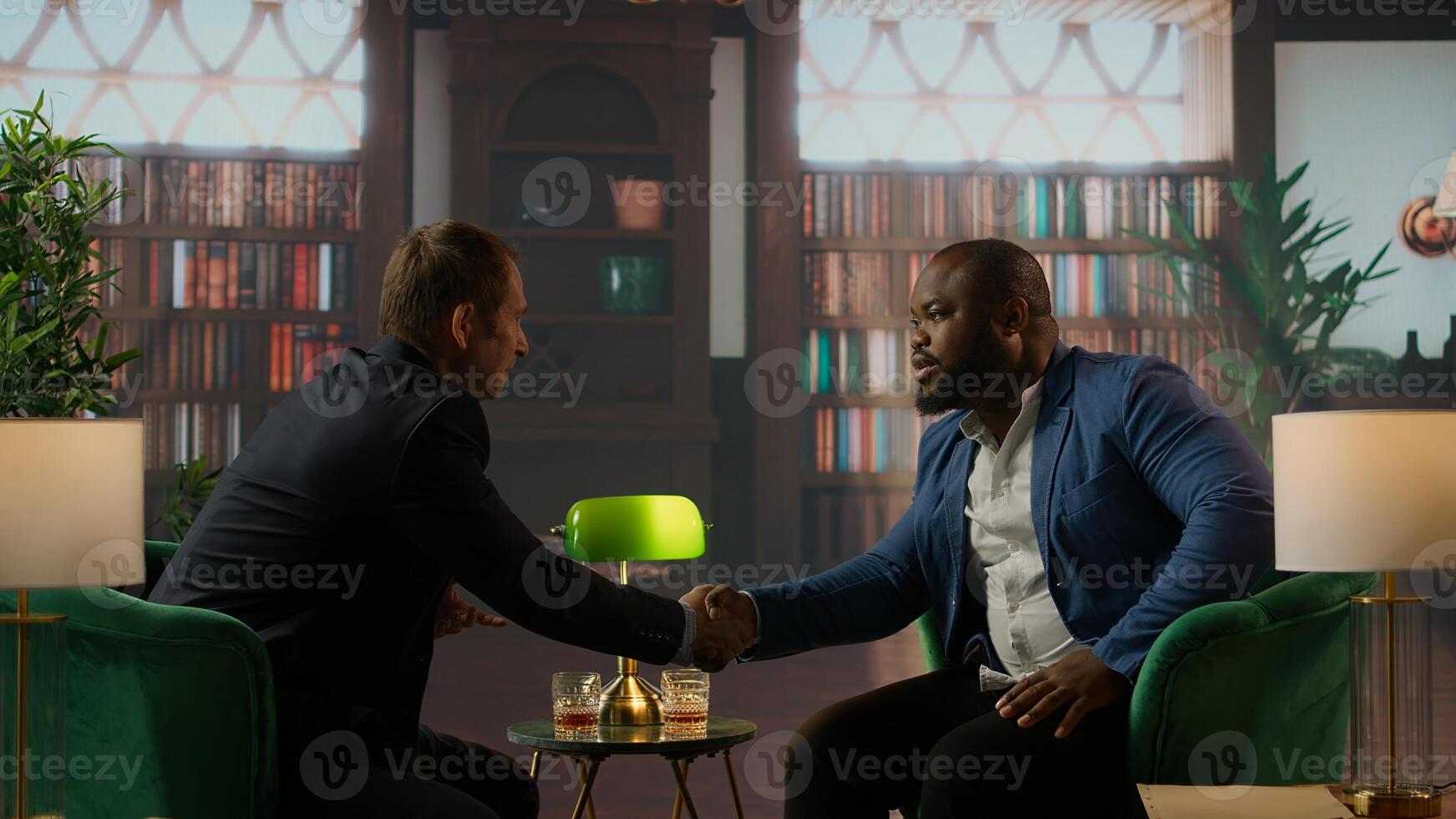 Diverse old money aristocrats shaking hands in agreement to unite their business, striking a deal over whiskey at the elite social club. Upper class gentlemen starting a new alliance. Camera A. photo