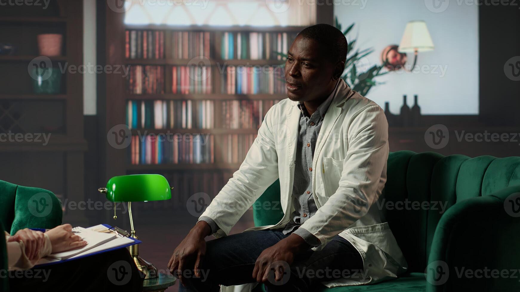 African american medic meeting with psychotherapist at counseling, sharing feelings of hopelessness and grief due to career trauma. Suffers PTSD and depression at the workplace. Camera B. photo