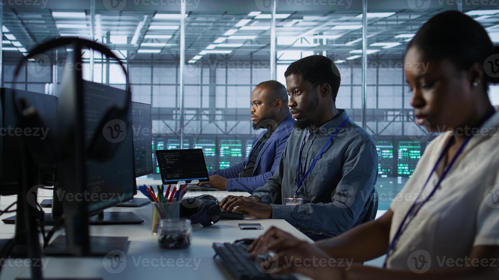 African american data center technicians implement AI predictive maintenance systems. Woman in server hub using artificial intelligence to identify hardware failures, camera A photo