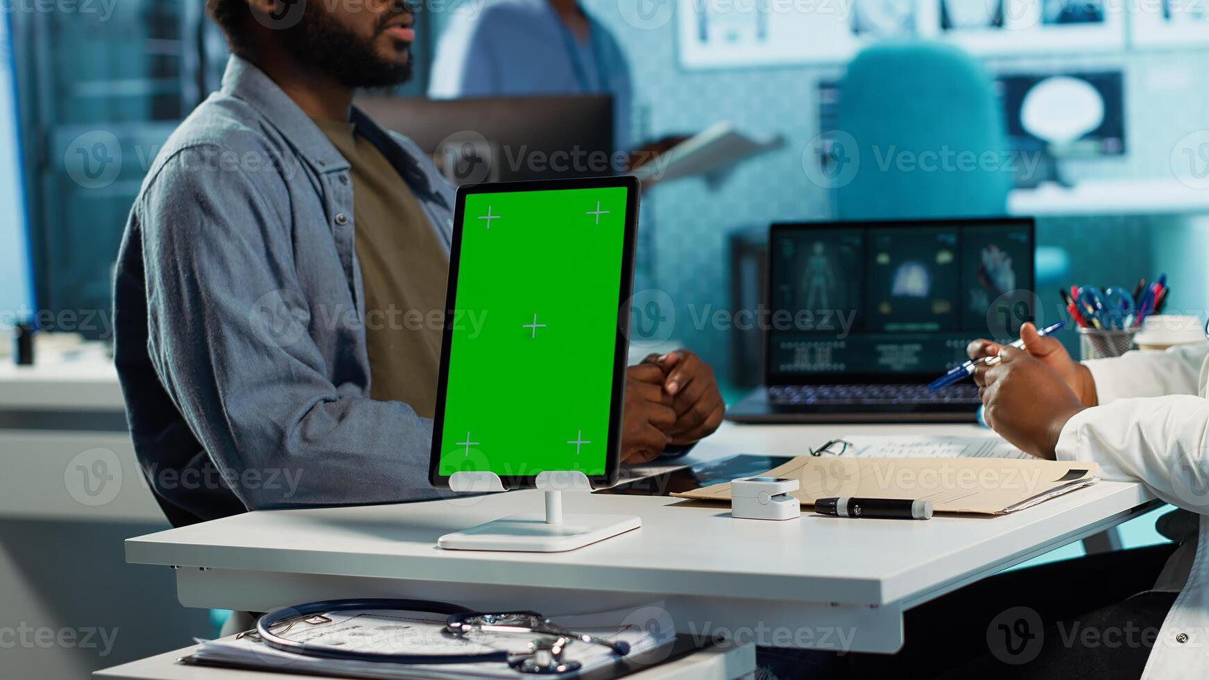 Black medic meets with patient next to isolated mockup display at the office, doing routine consultation and reviewing records for a treatment plan. Physician at private clinic. Camera A. photo