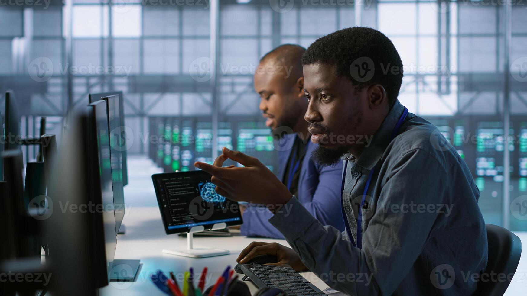 Cheerful coworkers in data center implementing AI predictive maintenance systems. Server room engineers using artificial intelligence to identify hardware failures impacting operations, camera A photo
