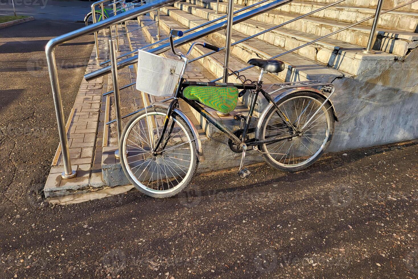 A bicycle with a basket stands near the porch with a railing. photo