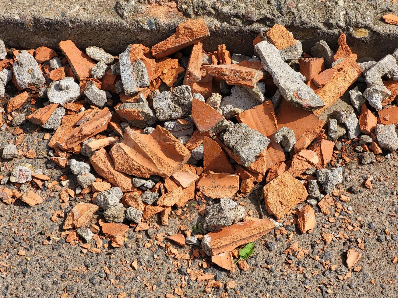 A pile of broken red bricks is lying on the grass repairing the wall of the house. photo