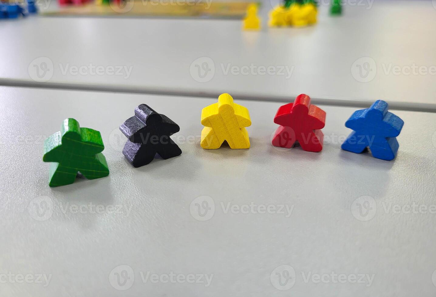A row of colorful wooden men on a gray background. Small figures of toy wooden colorful men. photo