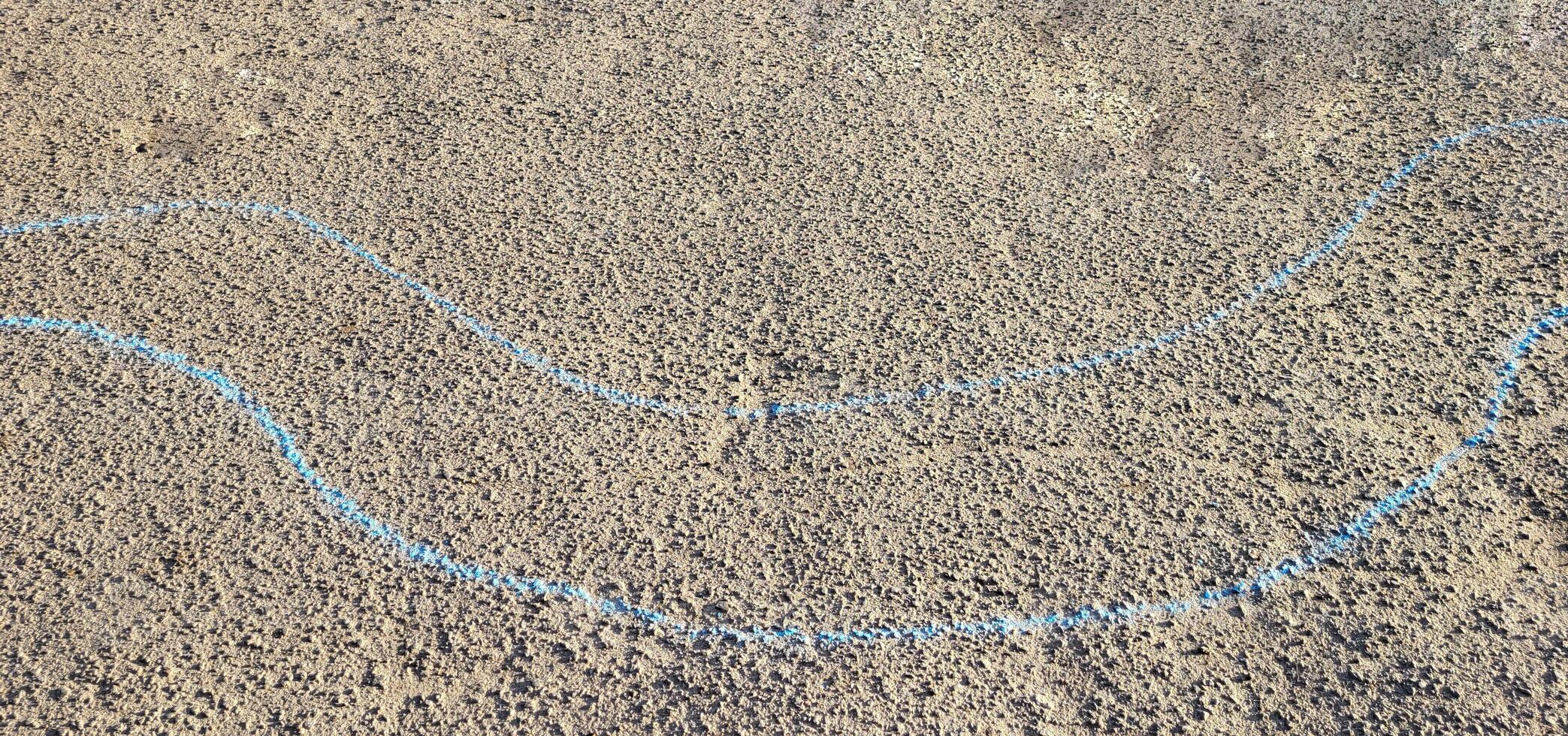Two blue curved wavy lines are drawn in chalk on the asphalt. photo