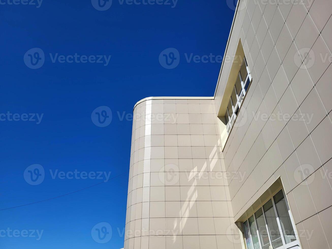 The facade of the house is made of large gray slabs on a bright sunny day against a blue sky. photo