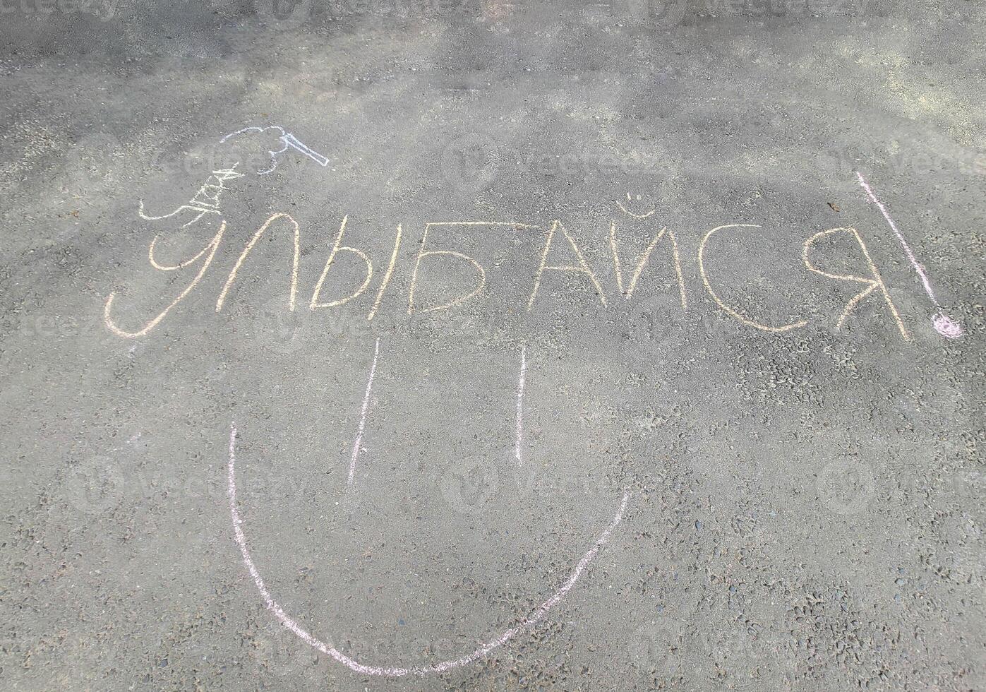 The word Smile is written on the gray asphalt in Russian letters. photo