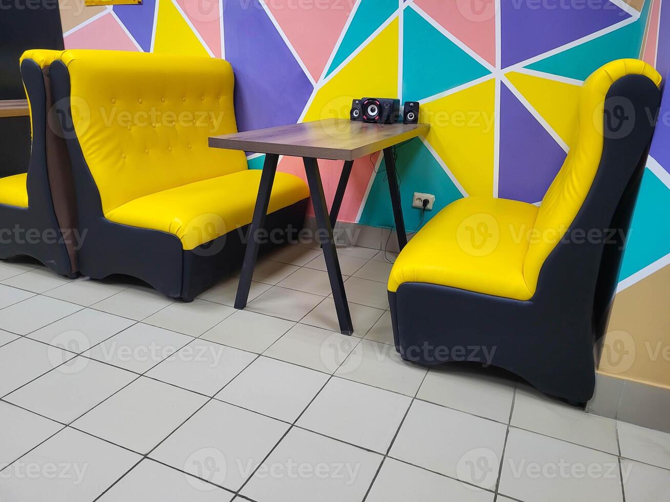 A table and bright yellow sofas in the cafe on the background of a multicolored wall. photo
