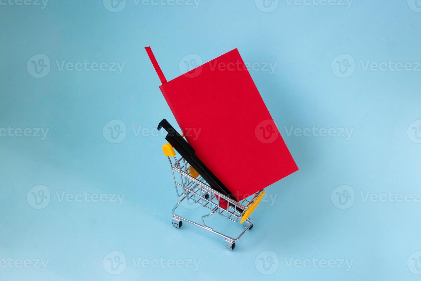 A red notebook and a black pen in a grocery cart. photo