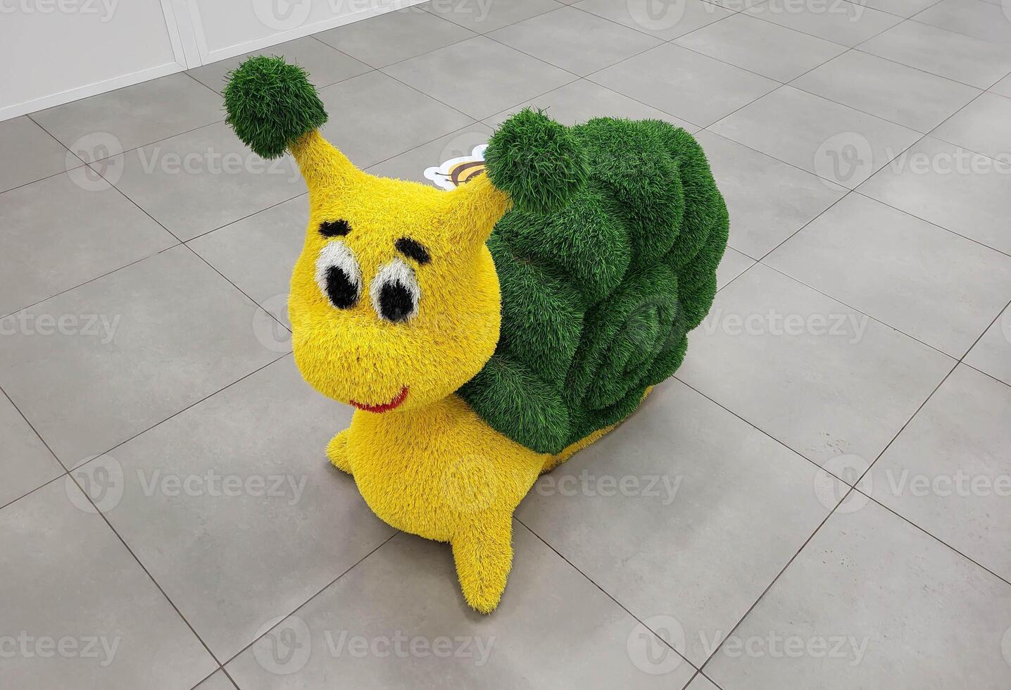 A funny artificial snail figurine topiary stands on the floor in a children's store photo