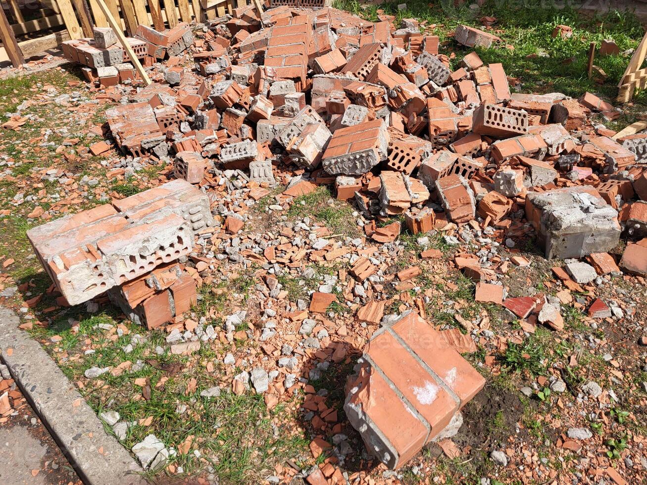 A pile of broken red bricks is lying on the grass repairing the wall of the house photo