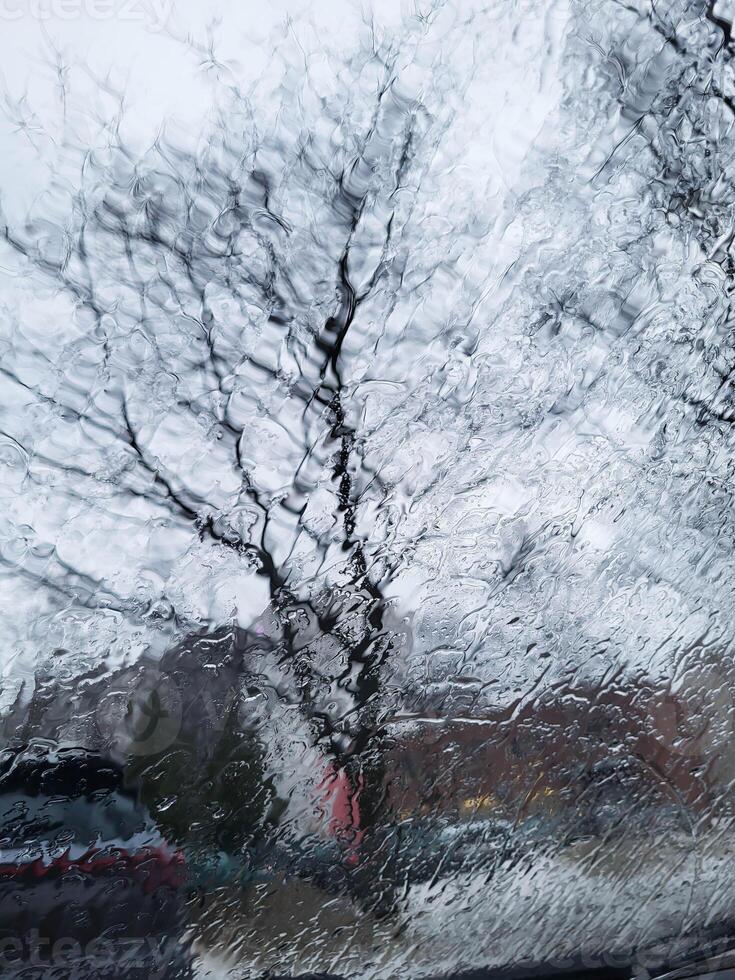 On a cloudy day, the windshield of the car is covered with rain streams. photo