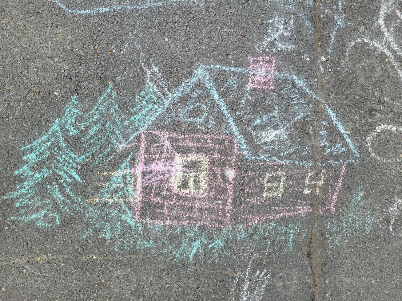 Drawing in multicolored chalk of a house with Christmas trees on the asphalt. photo