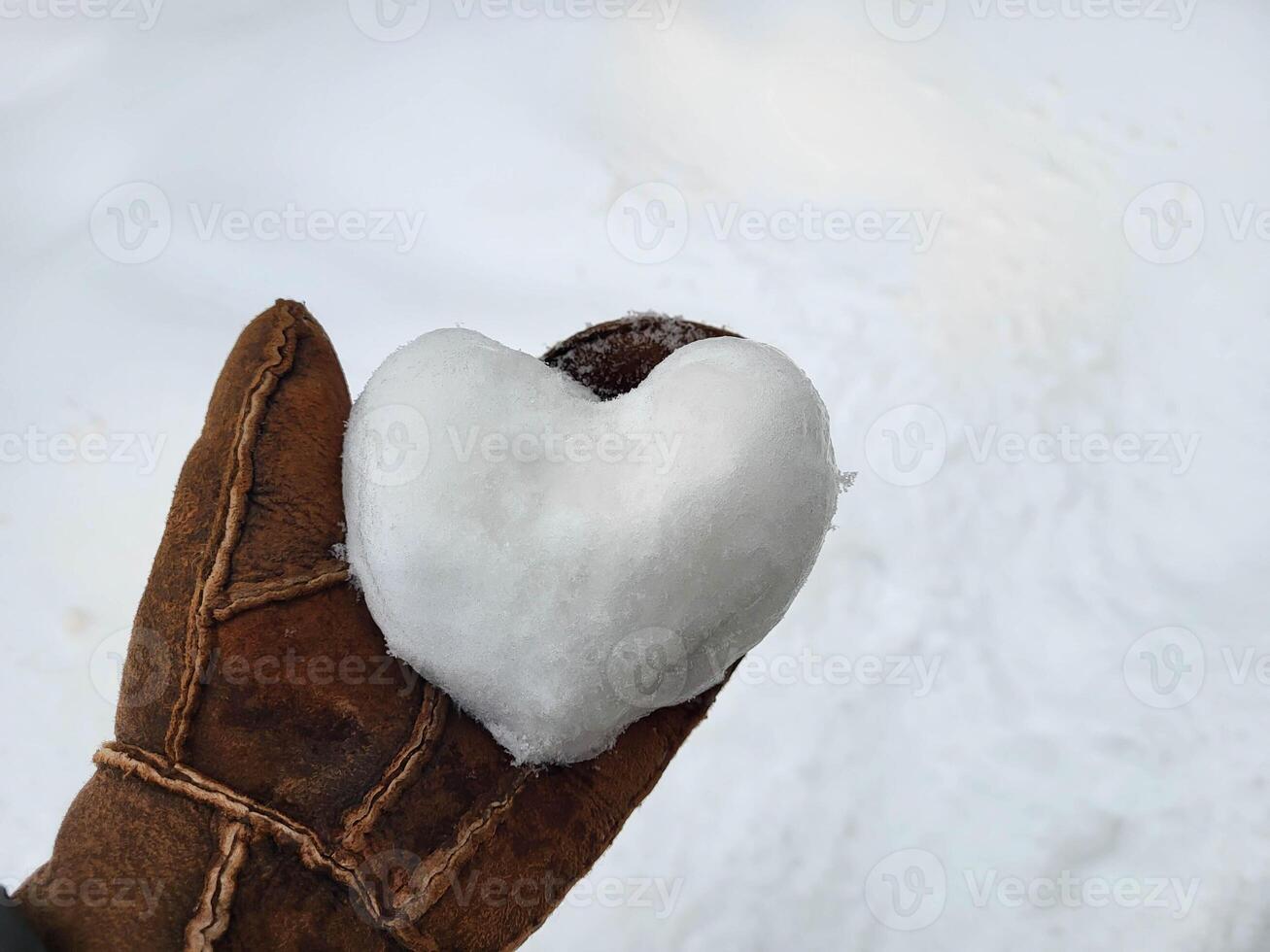 A heart made of snow lies on a brown tanned mitten. The concept of love, romance, Valentine's Day, Christmas photo