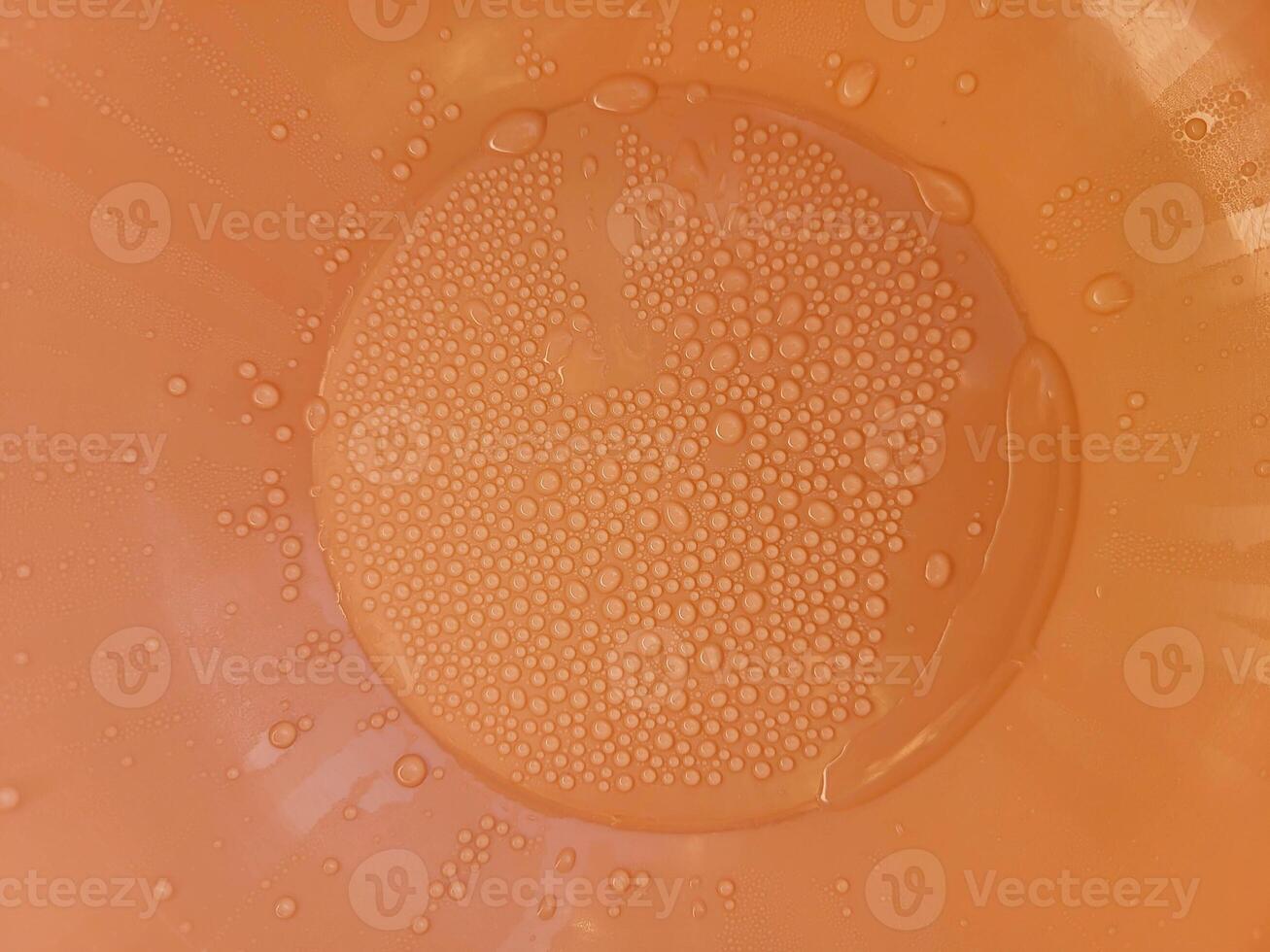 Orange plastic background with water droplets photo