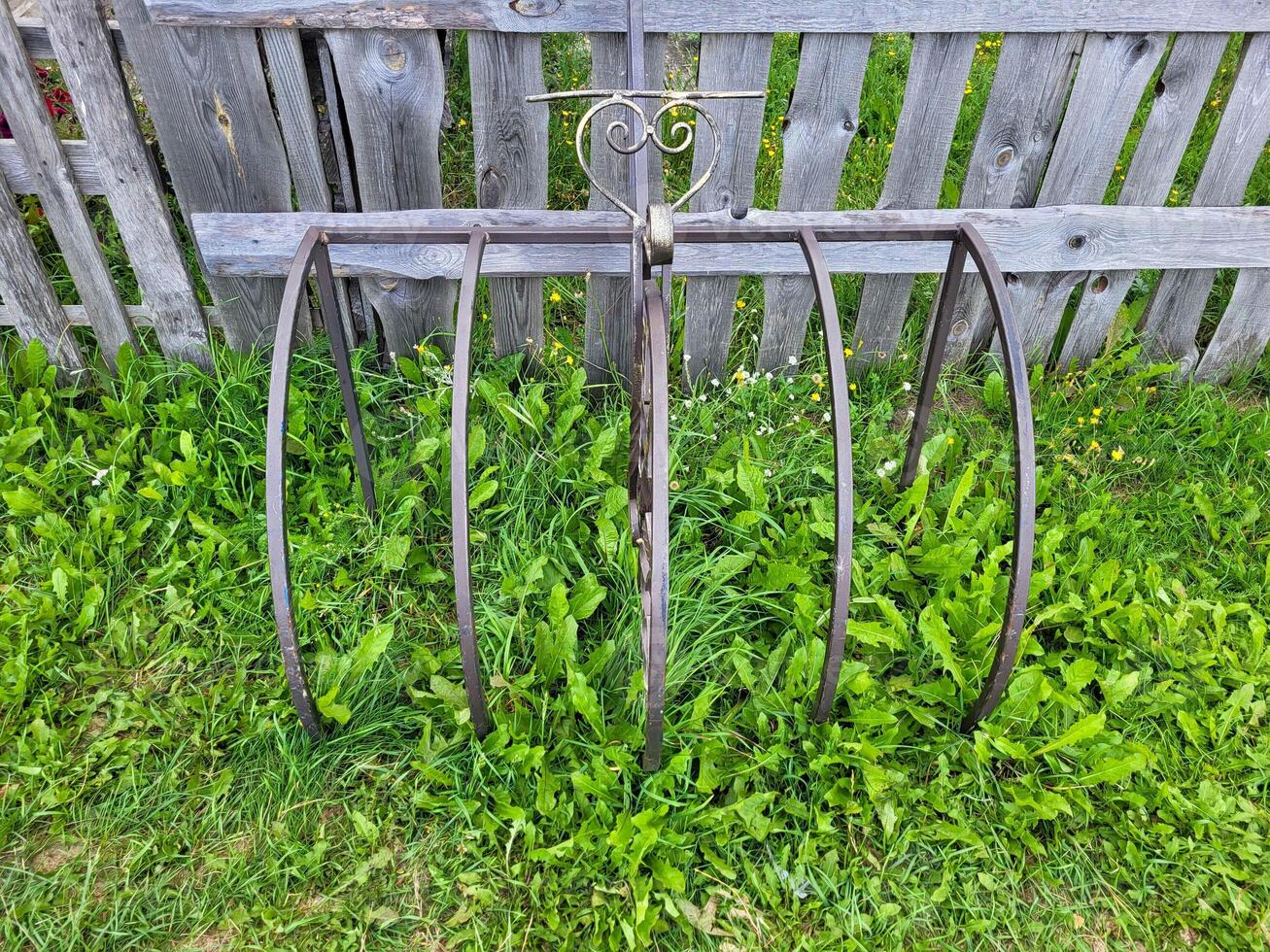 On a summer day, a forged rack with a heart for bicycles near a wooden fence on the green grass photo