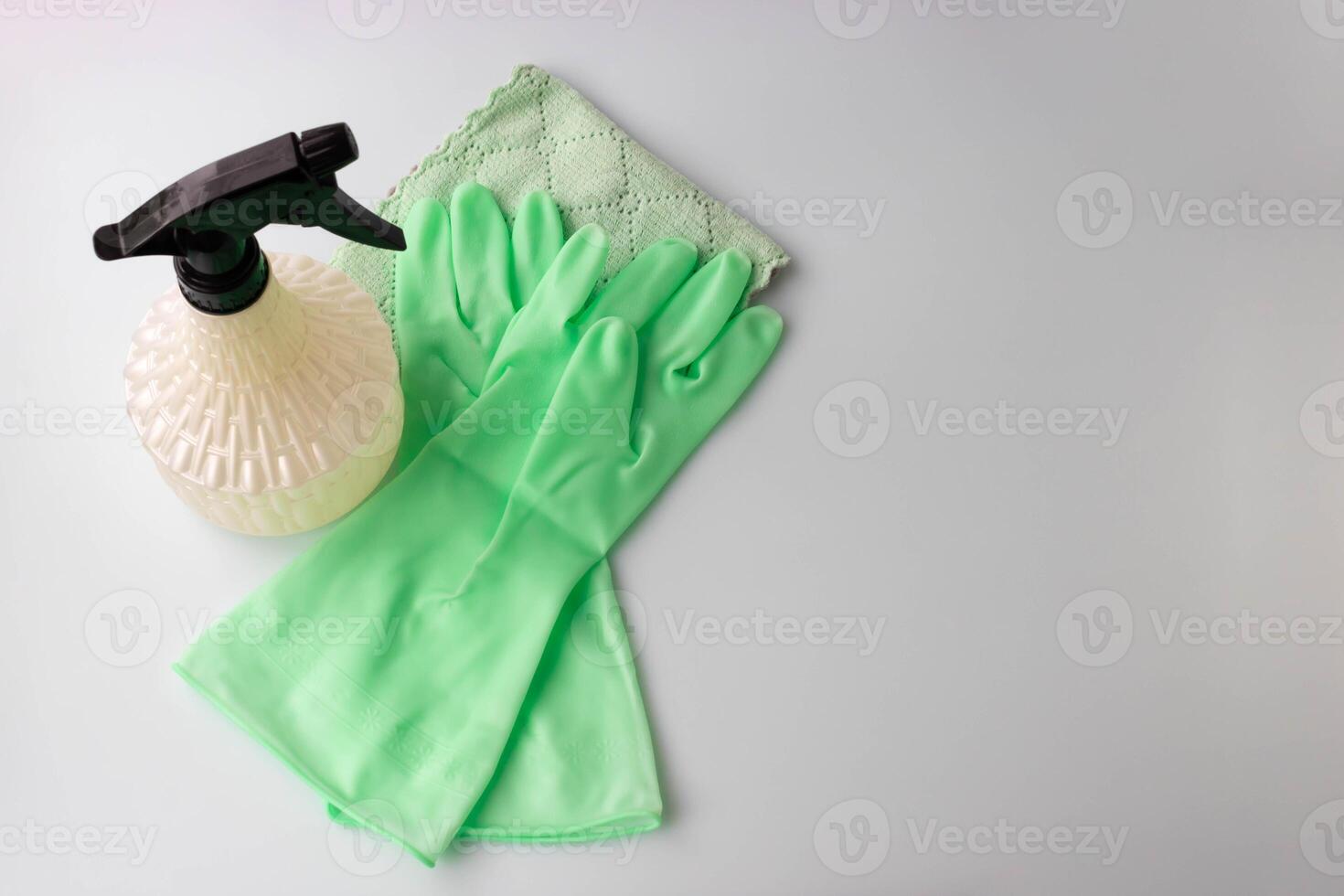 There are two light green rubber gloves, a napkin and a spray bottle on the table. A place for your text. photo