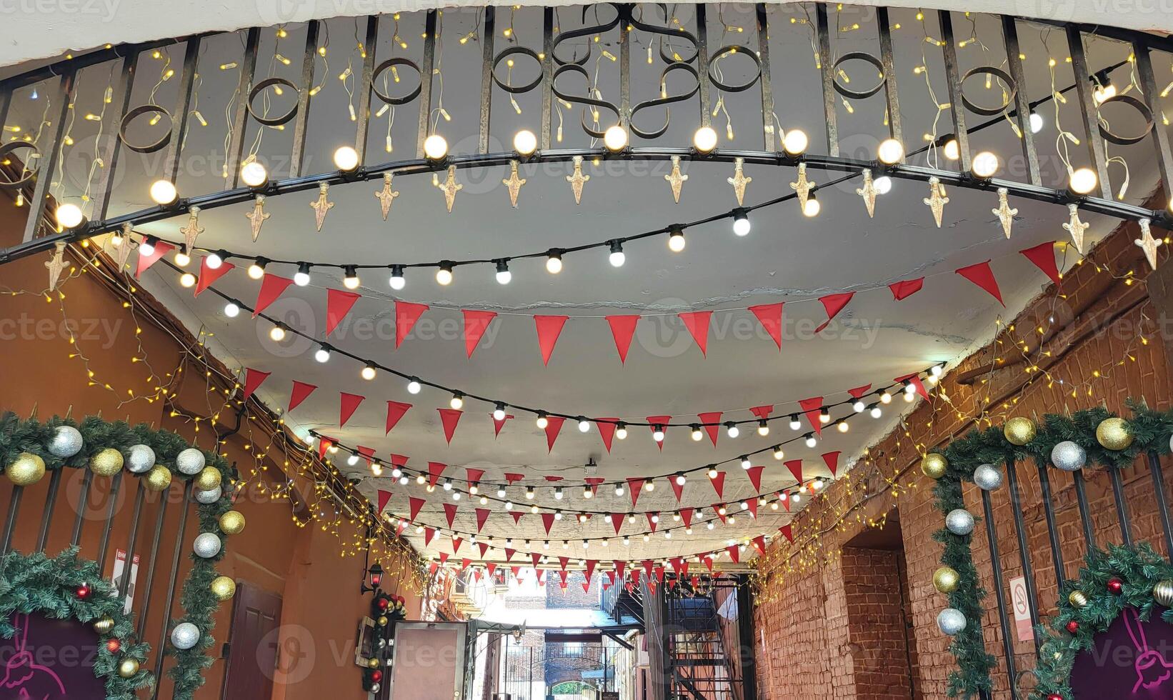Garlands of light bulbs and red flags hang in the arch between the houses. photo