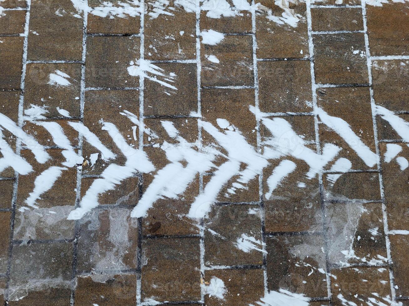 A snow trail from a wheel on the sidewalk on a cold winter day. photo