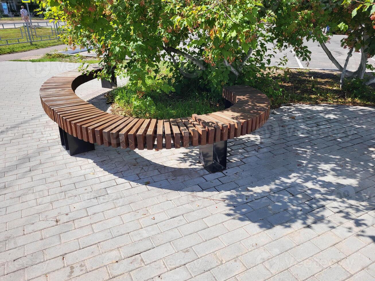 Semicircular wooden brown bench in the park on a bright sunny day photo