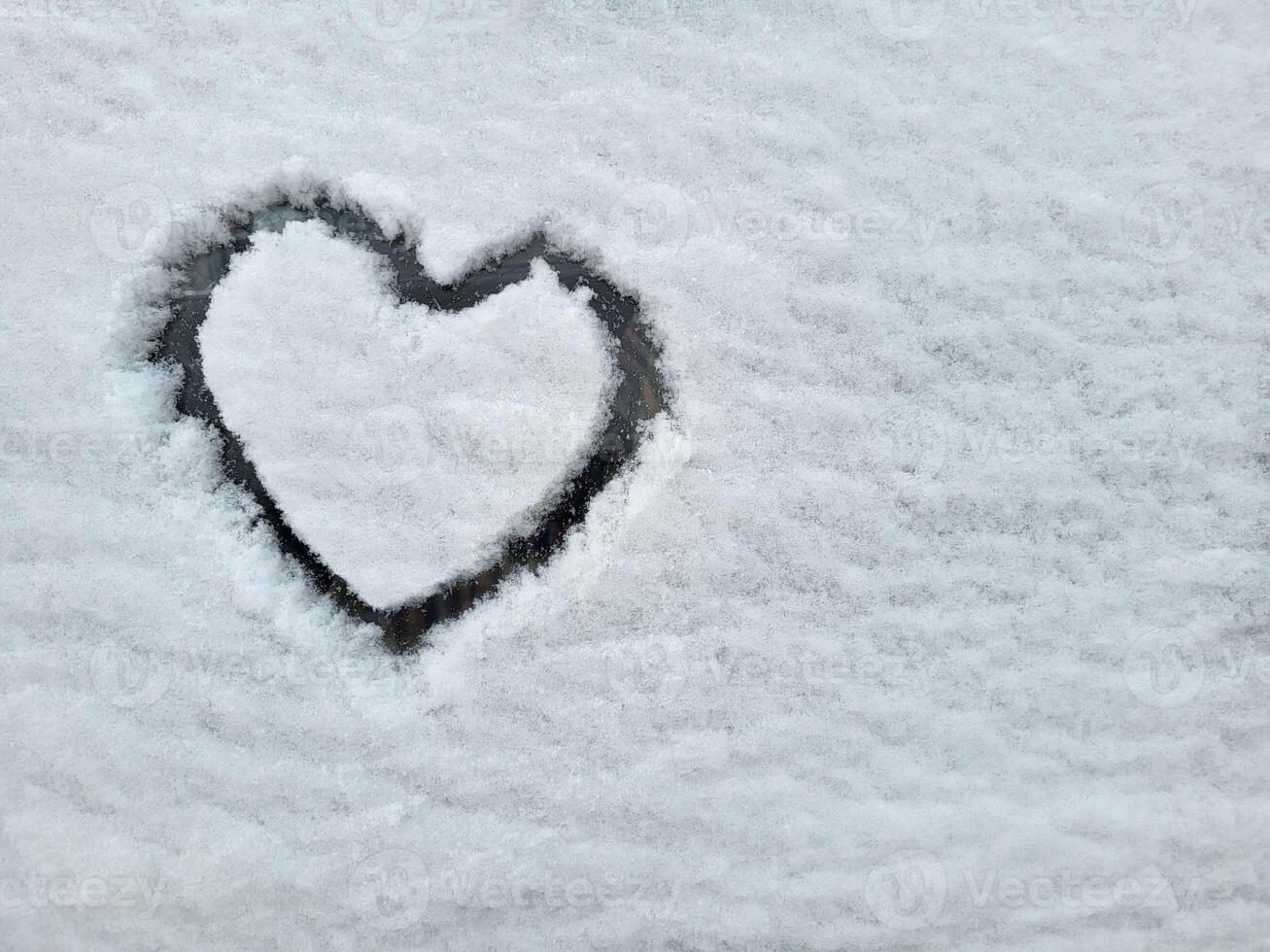 On the car window is a heart painted on fluffy snow. The concept of love, Valentine's Day, March 8th photo