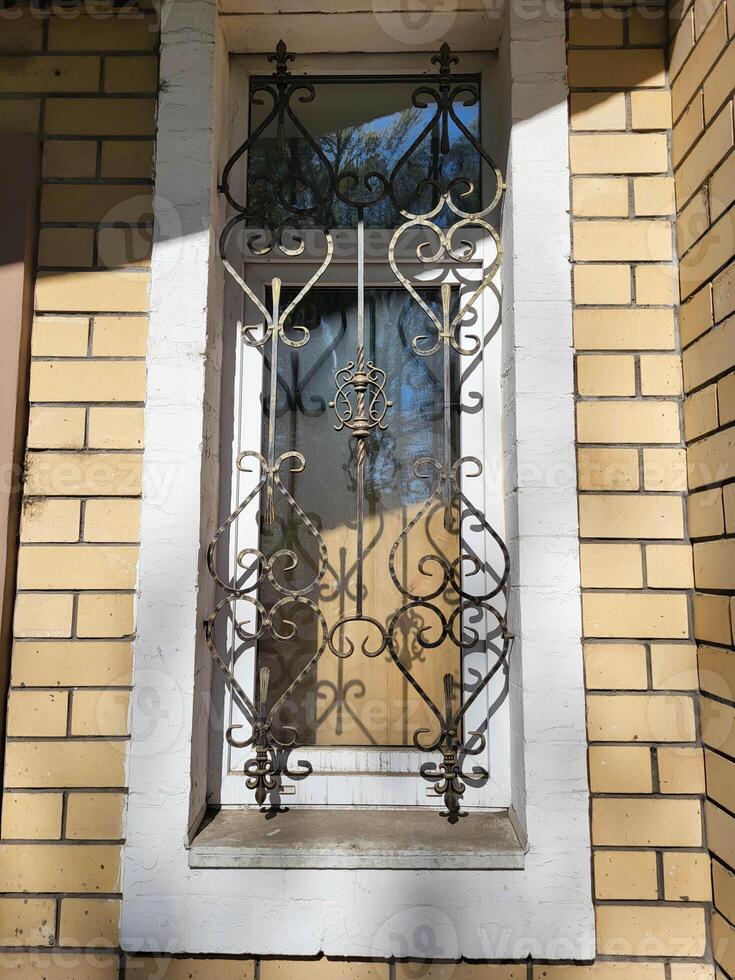 In a sunny spring facade with a narrow window with a wrought-iron grate. photo