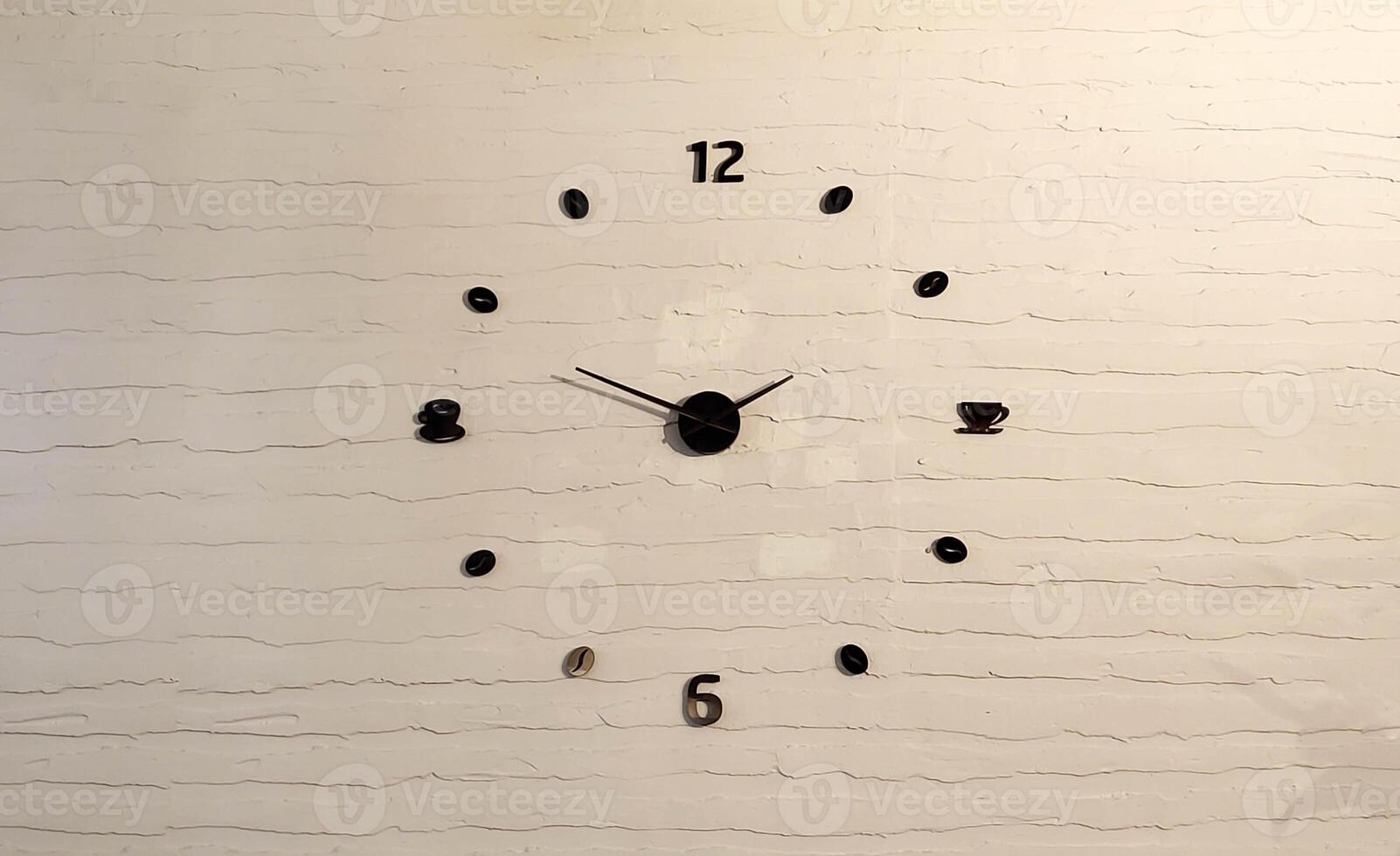 The black hands and numbers of the dial are on the background of a white brick wall photo